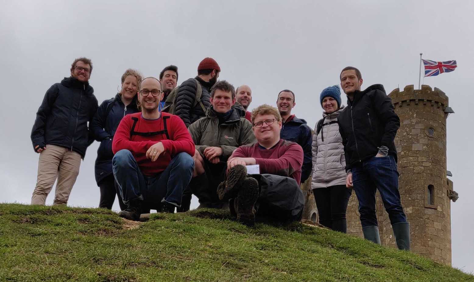 team standing and crouching in front of Broadway Tower