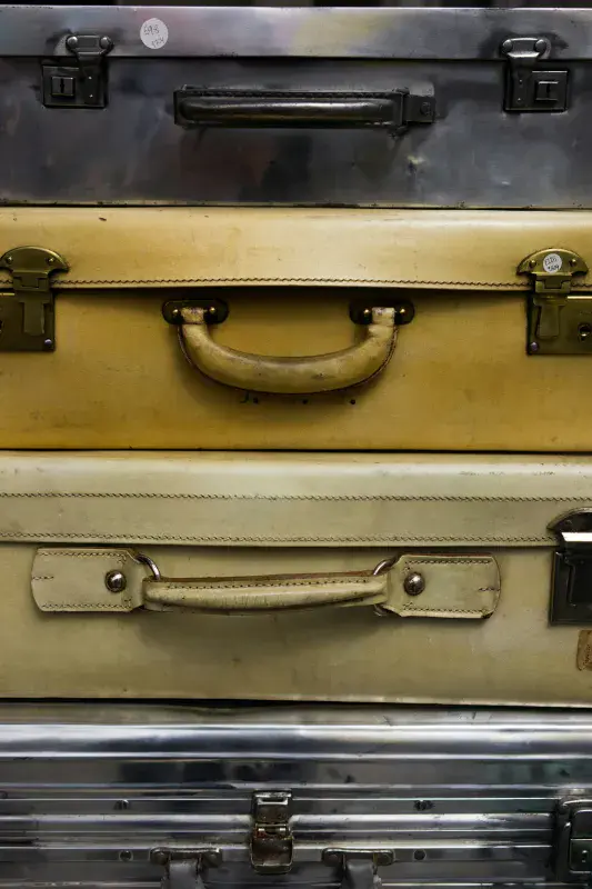 A vertical stack of four different vintage suitcases
