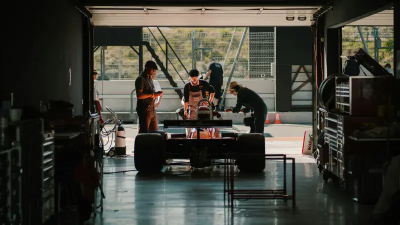 An engineering team examine their race car in the pit garage