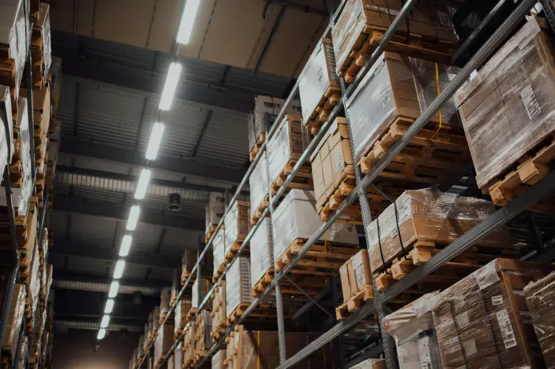 Looking up at tall warehouse shelves filled with boxes and pallets of goods