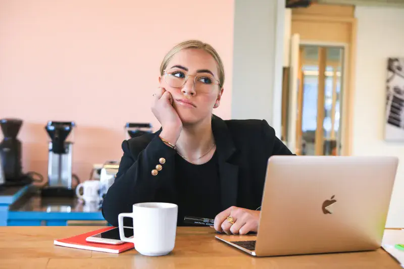 Girl at desk with computer, looking bored and unimpressed