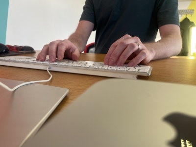 A software engineer at his desk, hands on his keyboard