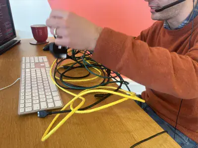 Technician at a desk, pulling at a a pile of tangled cables