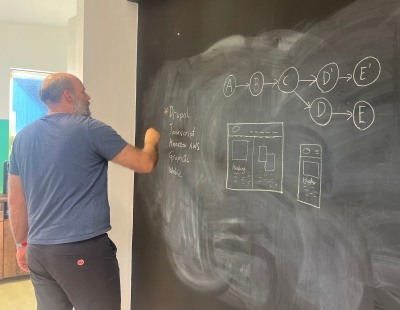Senior web developer drawing a problem diagram on a blackboard wall