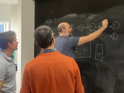 Web developers gathered round a blackboard wall as one draws out the problem diagram