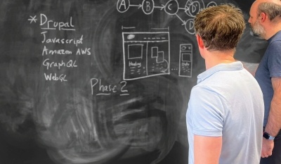 Two Computer Minds solving problems on a floor-to-ceiling blackboard