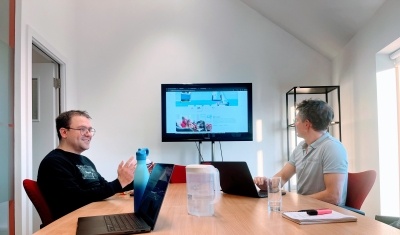 Two web developers at a large meeting room table with their laptops