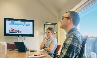 Web developers listening during a meeting, a large screen at the end of the table